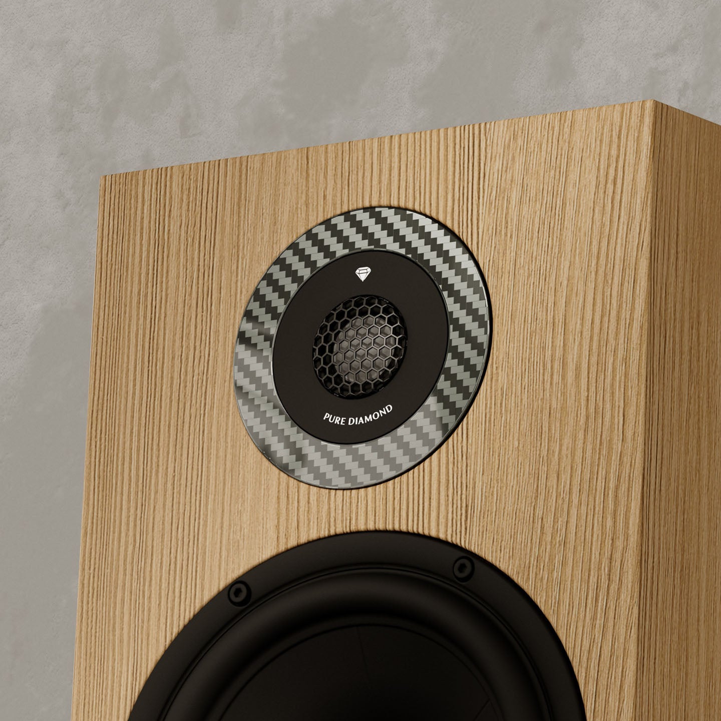 Wooden speaker with a carbon fiber patterned driver on a gray background